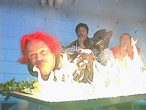 The Sinister Minister and Tajiri roast Mikey Whipwreck on a table - November to Remember 2000